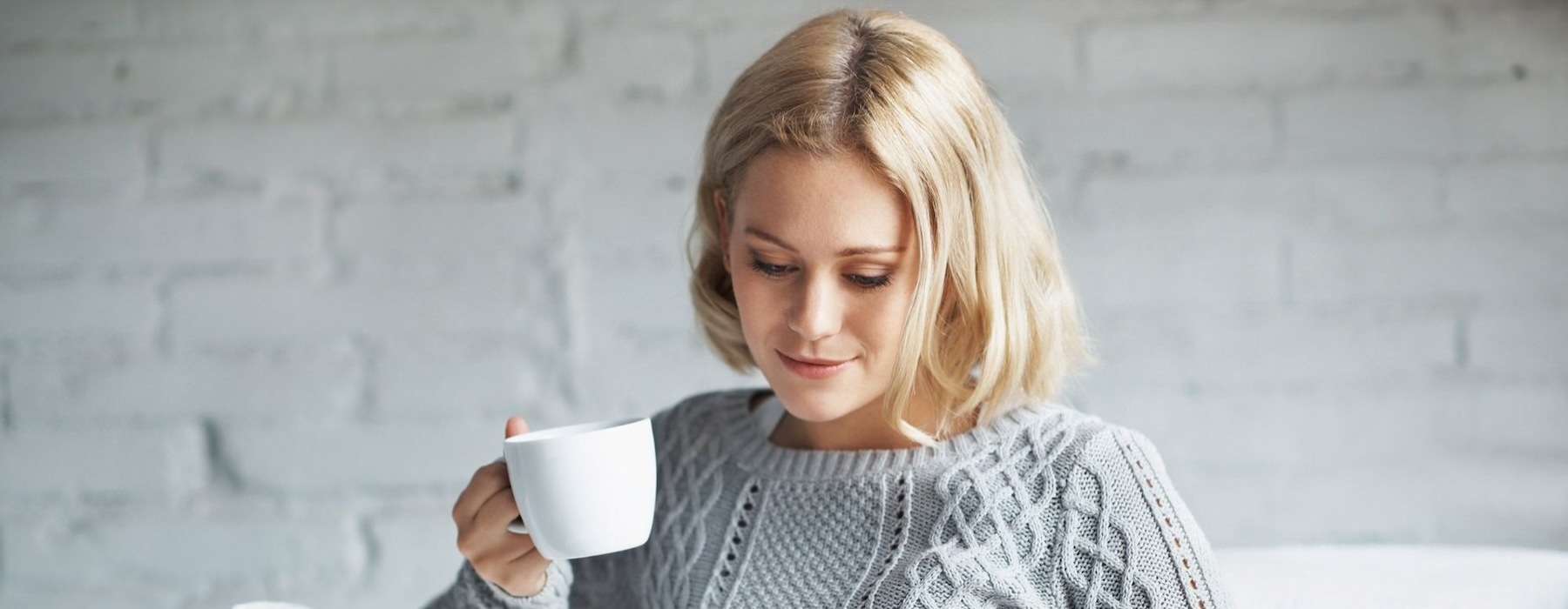 a person sitting down holding a cup looking at a tablet